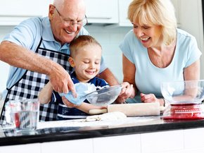 Senior couple and small kid preparing food in the kitchen